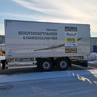 LKW-Anhänger mit Aufschrift Berufskraftfahrer und Fahrschulpartner
